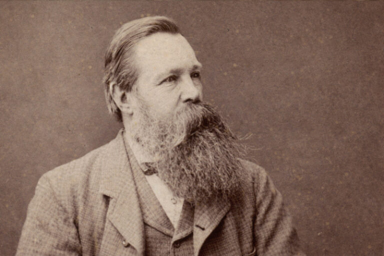 Politische Verfolgung in Deutschland 44 Porträt von Friedrich Engels im Sepia-Ton im 16:9-Format, mit langem Bart und Anzug, nach rechts blickend vor neutralem Hintergrund.