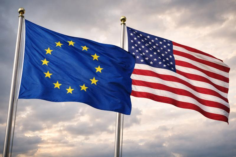 EU-Flagge und US-Flagge nebeneinander vor Himmel – Symbolbild für transatlantische Beziehungen zwischen Europäischer Union und USA