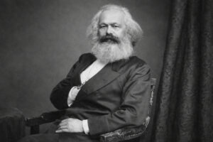 Karl Marx, historisches schwarz-weißes Porträt im Sitzen, mit langem Vollbart und Anzug, seitlich zum Betrachter gewandt (19. Jahrhundert)