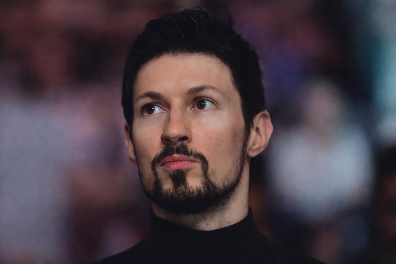 Nahaufnahme von Telegram-Gründer Pawel Durow mit dunklen Haaren und kurzem Bart, der zur Seite blickt, vor einem unscharfen Menschenmengen-Hintergrund.