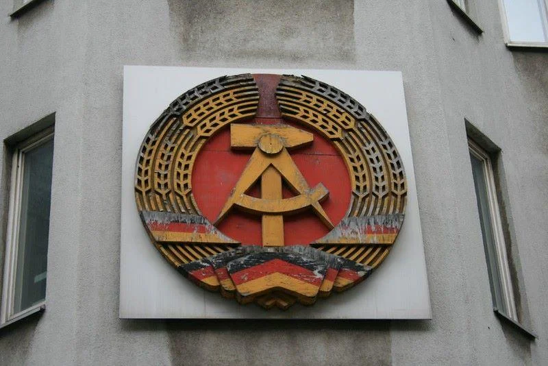 Zersetzung: Психологический террор Штази в ГДР 1 Wappen der DDR an Häuserwand