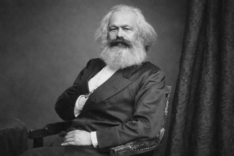 Karl Marx: Der staatenlose Gehetzte im Visier der europäischen Geheimpolizei 1 Karl Marx, historisches schwarz-weißes Porträt im Sitzen, mit langem Vollbart und Anzug, seitlich zum Betrachter gewandt (19. Jahrhundert)